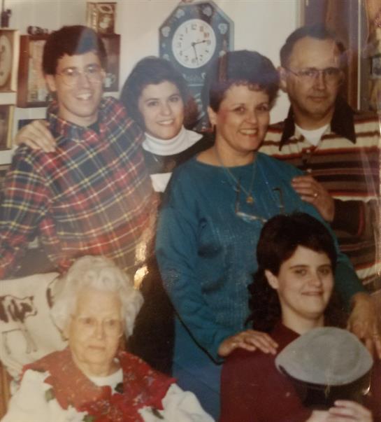 A cheerful family poses together in a decorated living room, celebrating a special occasion.