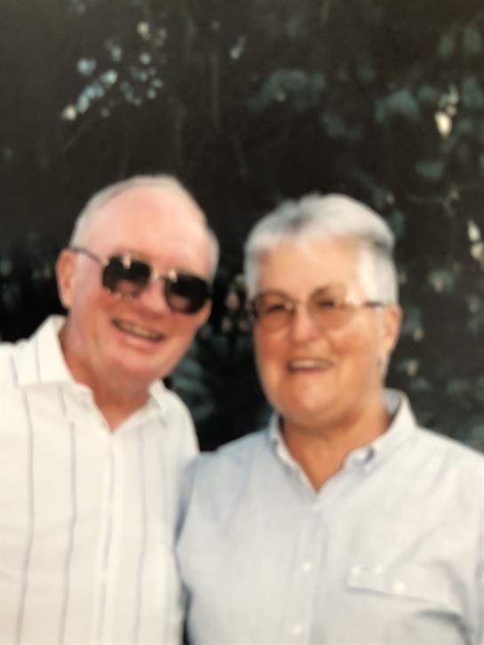 Two elderly individuals share a joyful moment outdoors, smiling and enjoying their time together.