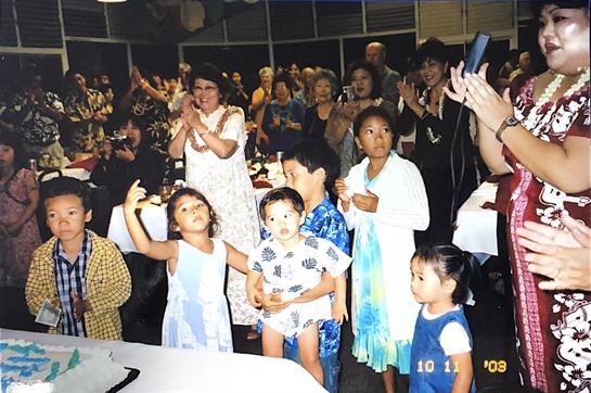 A joyful family gathering with kids and adults celebrating and clapping in a festive atmosphere.