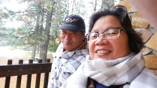 Two friends take a cheerful selfie together amidst a beautiful forest landscape.