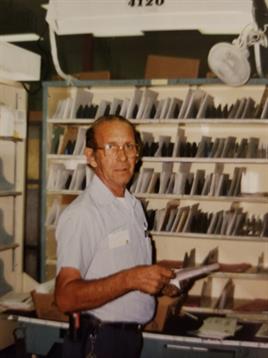 An older man reviews papers in an organized office, reflecting daily work life.
