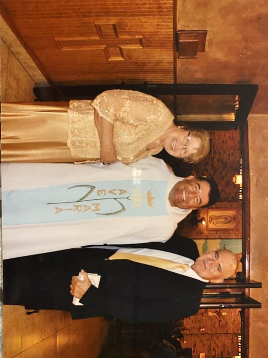 Three individuals are gathered, dressed elegantly, celebrating together during a special occasion.