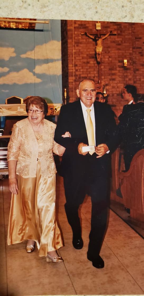 An elderly couple enjoys a special moment while walking arm in arm at a festive gathering.