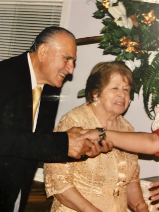 An elderly couple joyfully engages with a younger family member during a home celebration.