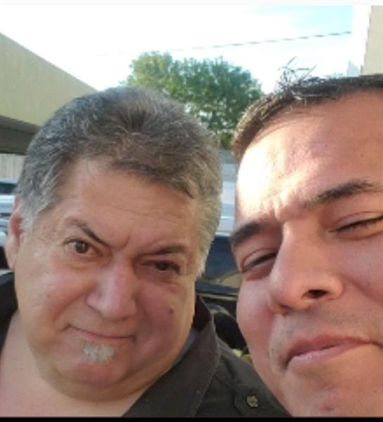 Two friends enjoy a cheerful moment together in a city setting on a bright afternoon.