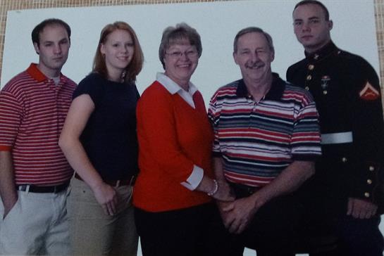 Five family members pose together happily, showcasing their outfits and capturing a joyful moment.