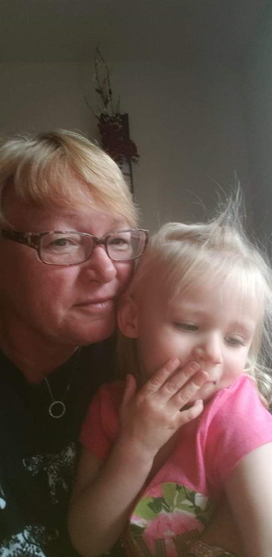 A loving grandmother embraces her granddaughter while they enjoy time together indoors.