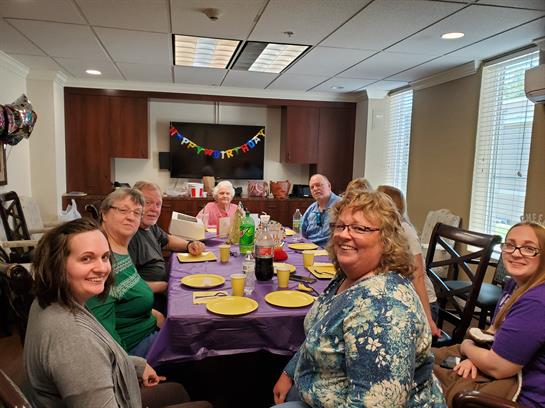 A cheerful group of friends and family enjoy a celebration together around a decorated table.