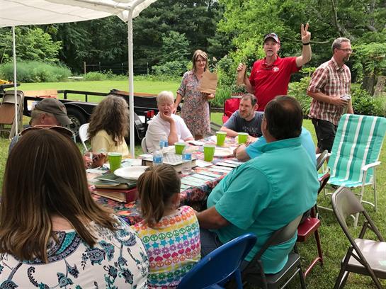 Friends enjoy lively conversations and activities under a tent in a beautiful outdoor park.