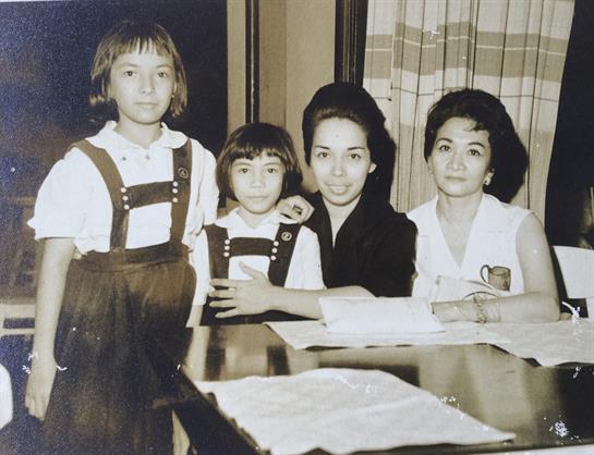 Four individuals, two adults and two children, share a warm moment indoors at a table.