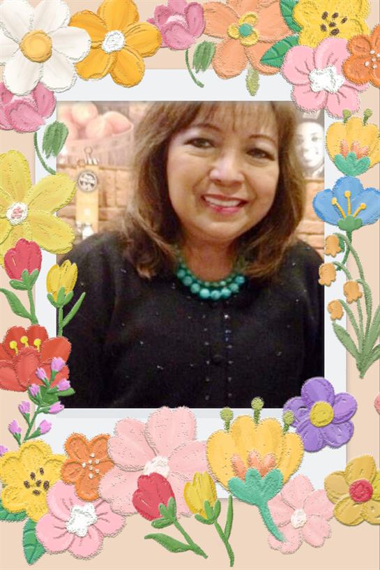 A cheerful woman smiles among vibrant flowers in a decorative outdoor frame.