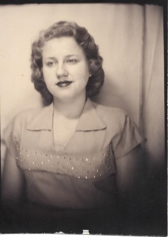 Curly-haired woman in a vintage dress poses in a studio, capturing a timeless moment.