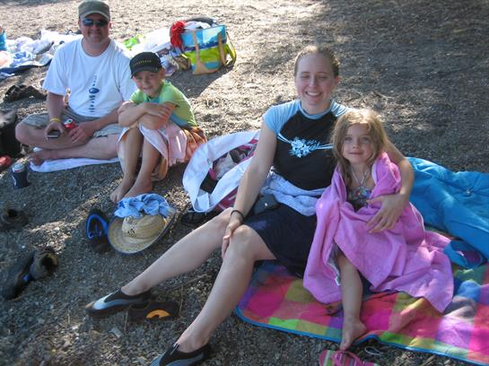 A family of four enjoys a sunny afternoon at the park, relaxing on blankets together.