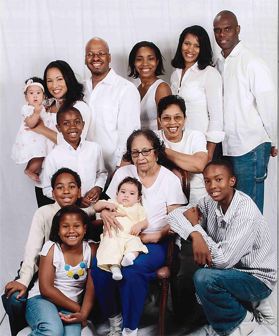 A joyful family gathers for a portrait, featuring three generations and displaying affection.