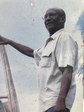 A man confidently demonstrates traditional fishing methods by the clear shoreline.