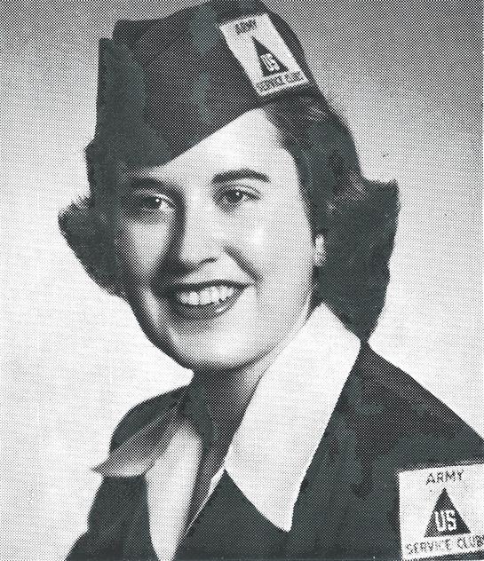 A woman poses confidently in a military uniform, showcasing her rank insignia and gleaming smile.