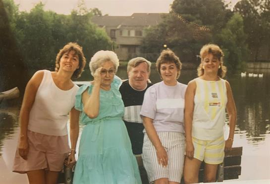 Six friends gather by the water, smiling and enjoying each other's company on a warm day.