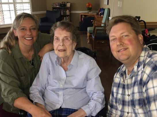 Family visits elderly relative in cozy living room, sharing smiles and warm moments together.