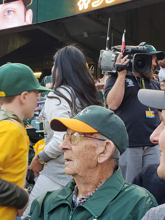 Fans gather at the stadium, sharing excitement during a close, sunny baseball game.