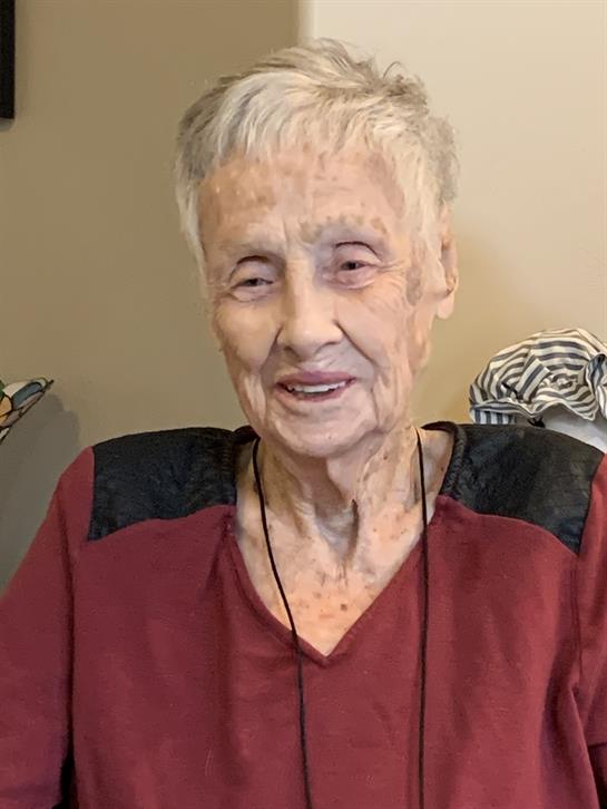 Elderly woman shares stories while seated in a comfortable living room, radiating warmth and joy.