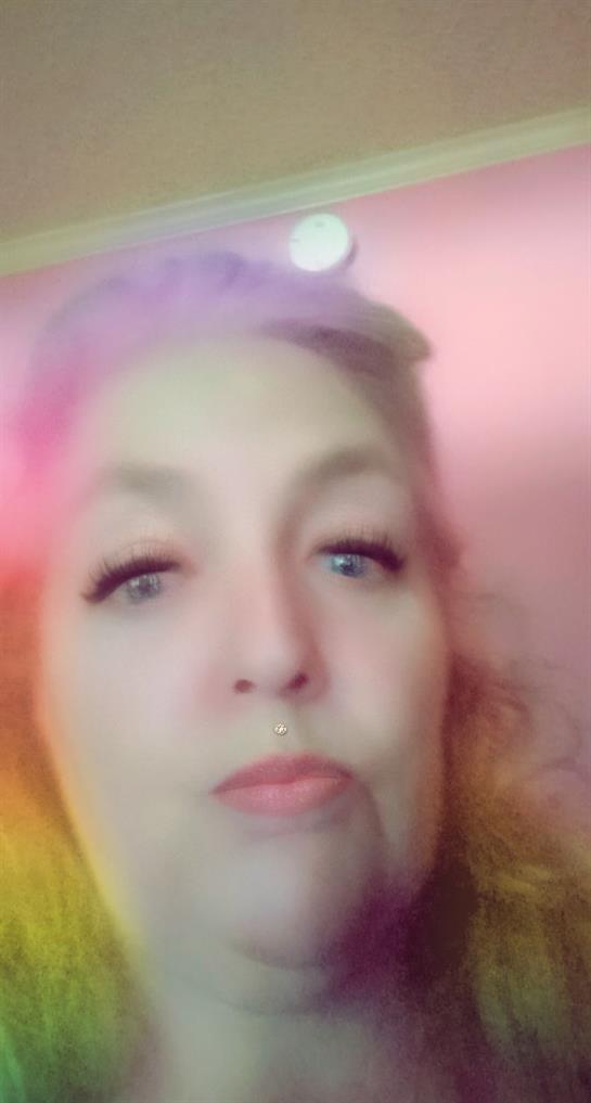 A woman showcases her vibrant hair and expressive look against a colorful backdrop.