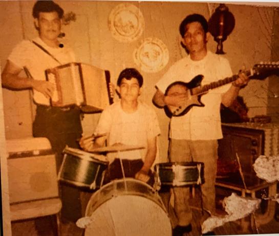 Three musicians play instruments in a warm, intimate home setting, creating a joyful atmosphere.