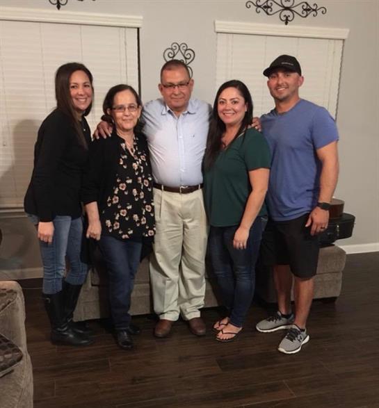 Family members smile and pose together in a living room, highlighting a joyful reunion.