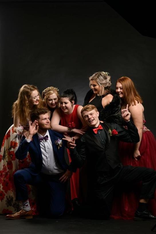 Friends pose joyfully in formal wear, showcasing lively expressions and playful interactions.