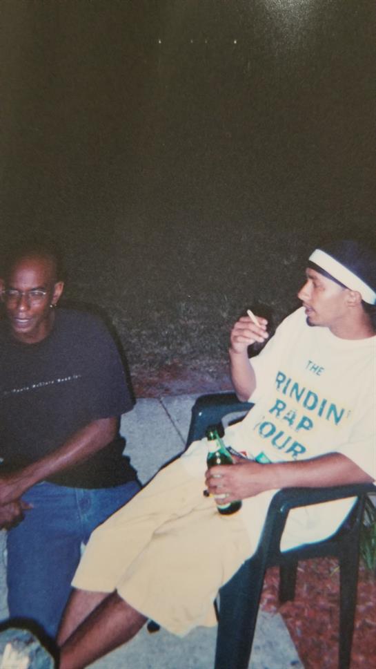 Two men enjoy a relaxed evening, chatting while seated outside in a warm atmosphere.