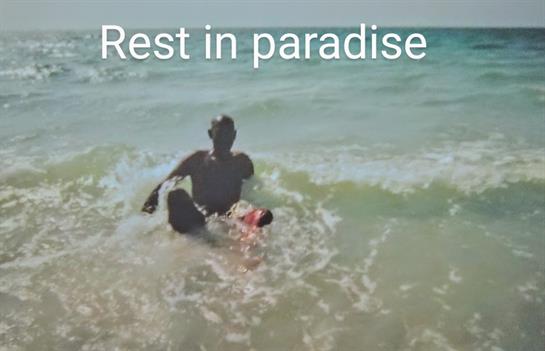 A person enjoys their time by the ocean, playing in the waves during sunset.
