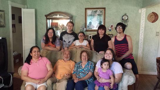 Family members gather in a warm living room, sharing smiles and laughter during a reunion.