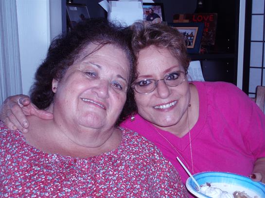 Two women smile happily while sitting close together, enjoying ice cream and each other's company.
