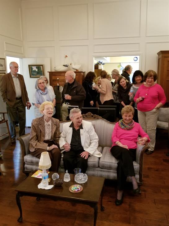 A group of people socialize in a warm living room, enjoying each other's company and refreshments.