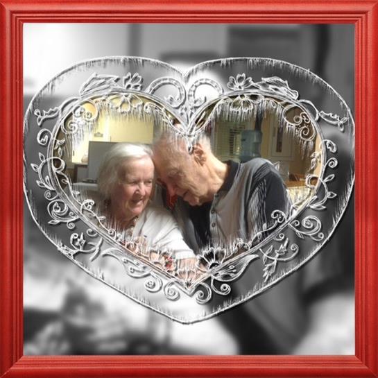 An elderly couple leans close together, sharing smiles and warmth in a heart-shaped frame.