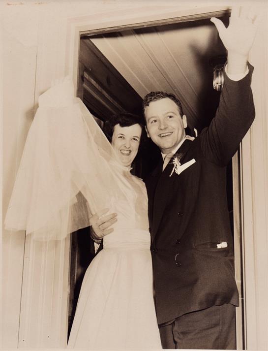 Newlyweds leave the venue, beaming with happiness and waving at friends and family outside.