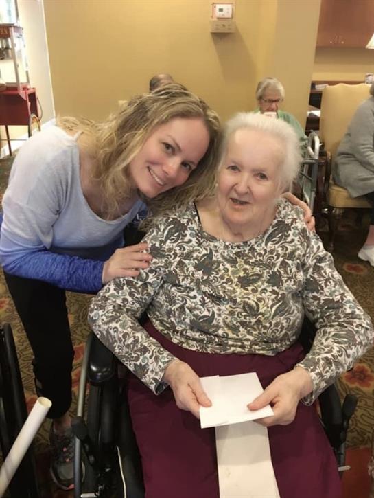 Caregiver interacts warmly with elderly resident in nursing home, fostering companionship and joy.