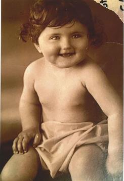 A smiling baby sits comfortably, exuding joy and innocence in a soft, nostalgic environment.