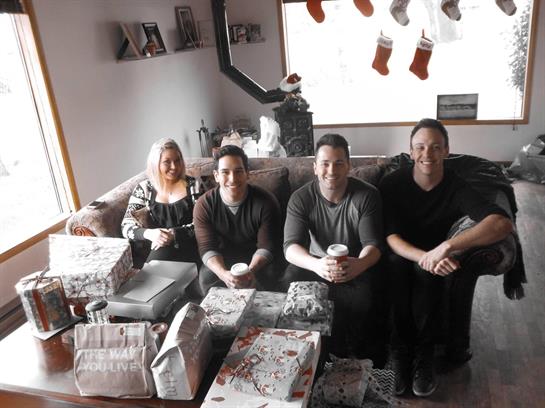 Family members enjoy each other's company in a decorated living room filled with gifts.