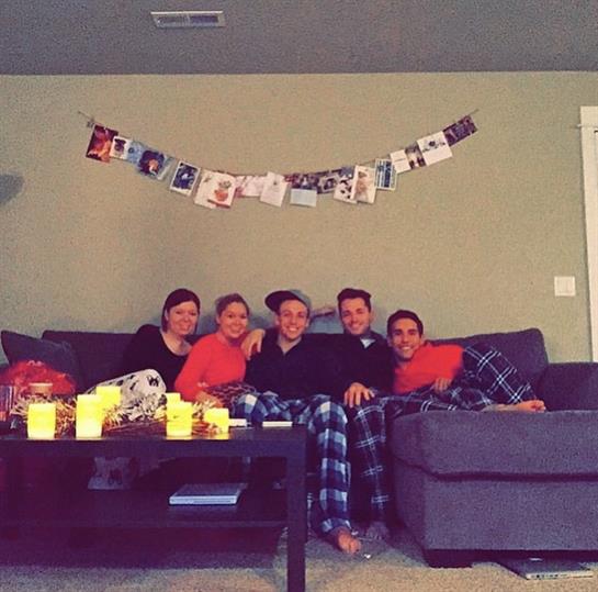 Five friends relax together on a couch, sharing laughter and warmth during a holiday celebration.