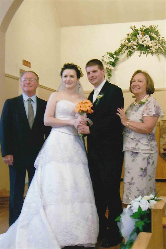 A newlywed couple poses with family inside a church, celebrating their special day together.