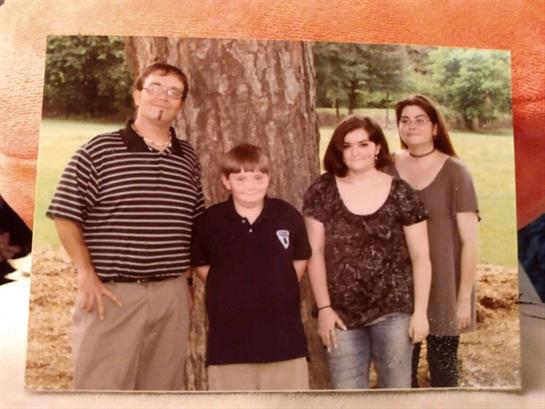 Group of four people standing together by a tree, enjoying their time outdoors in the park.