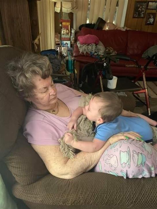 Grandmother enjoys affectionate interaction with her baby in a warm living room setting.