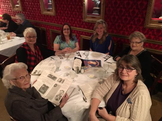 Friends gather around a table in a warmly decorated restaurant, sharing laughter and conversation.