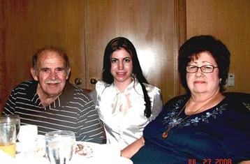 Three family members share smiles and laughter while seated at a table during a meal.