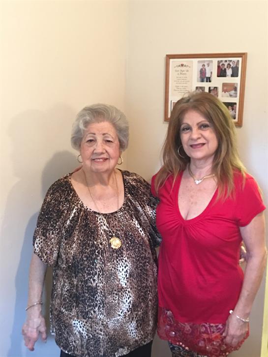 Two women stand together, showcasing the bond between generations in a warm home environment.