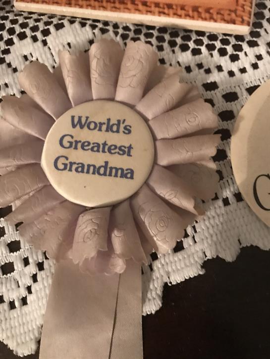 A ribbon is displayed on a lace tablecloth, honoring a grandmother for her contributions and love.