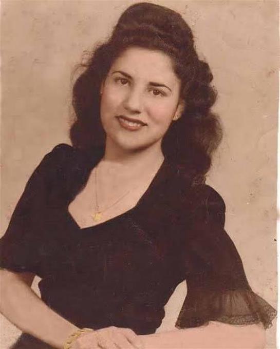 A young woman smiles warmly in a black dress, evoking nostalgia and charm from another era.