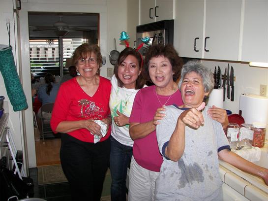 Four women enjoy a joyful moment together in the kitchen, sharing laughter and companionship.