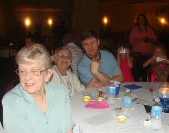 Friends gather around tables, sharing laughter and conversation during a vibrant evening event.