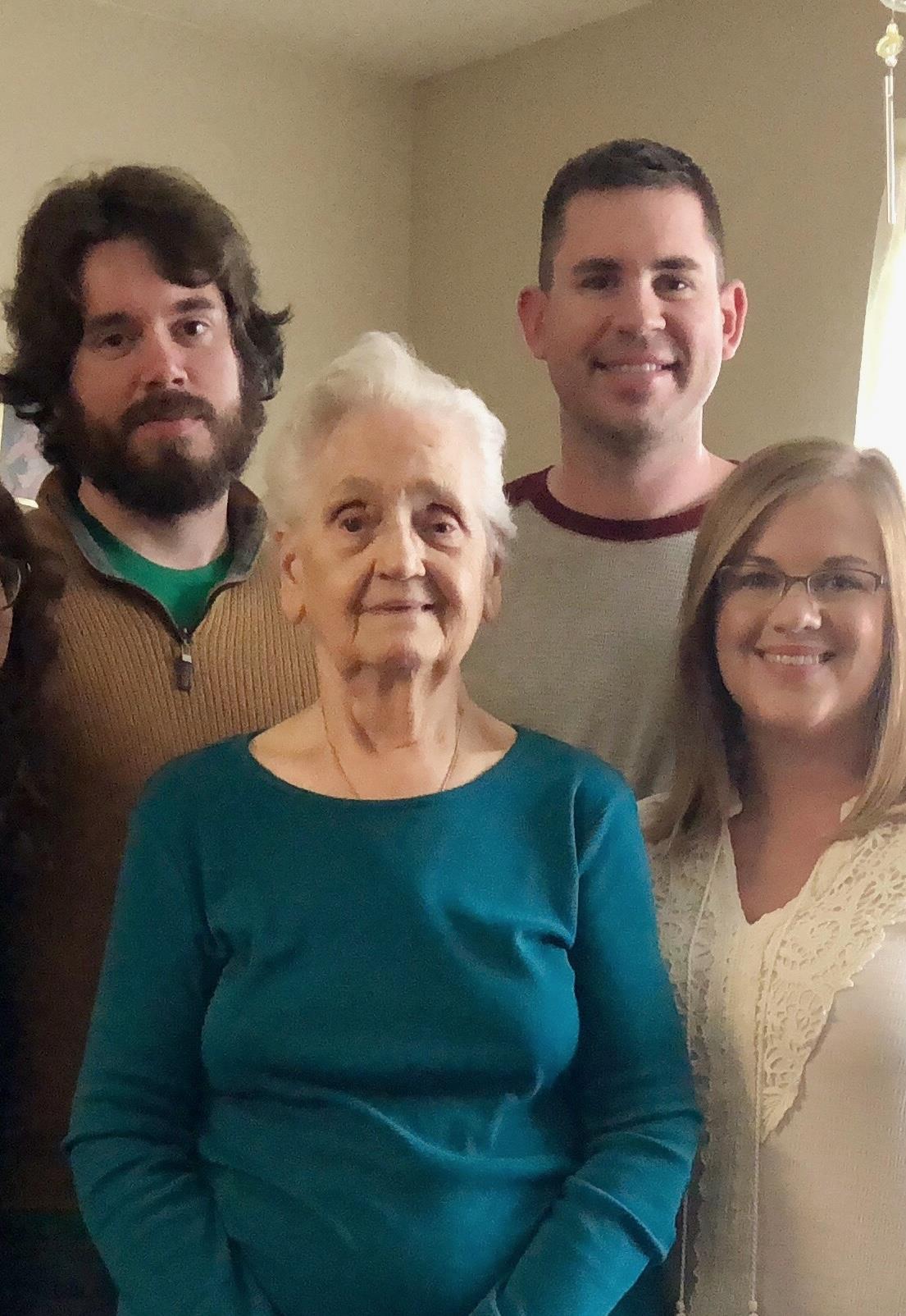 Family members stand together in a warm living room, celebrating a milestone with joy and laughter.